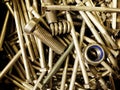 Many iron fasteners laying on top of each other with a big bolt at the front in a pile