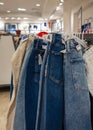 Many jeans hanging on a rack. Row of pants denim jeans hanging in closet. Jeans on the hangers on a sale