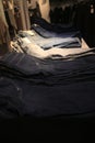 Many jeans piled up and sorted by their color ranging from black to light grey to a typical blue jean color