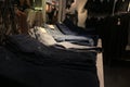 Many jeans piled up and sorted by their color ranging from black to light grey to a typical blue jean color