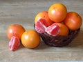 Many juicy orange shiny ripe grapefruit and some pieces of pilled skinned fruit in a basket on oak tree background. Royalty Free Stock Photo