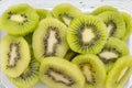 Many kiwi slices are placed in a glass crisper. Kiwifruit slices without peel