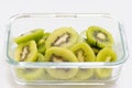 Many kiwi slices are placed in a glass crisper. Kiwifruit slices without peel