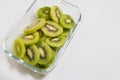 Many kiwi slices are placed in a glass crisper. Kiwifruit slices without peel