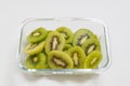 Many kiwi slices are placed in a glass crisper. Kiwifruit slices without peel