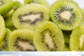 Many kiwi slices are placed in a glass crisper. Kiwifruit slices without peel
