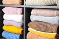 Many knitted winter clothes stacked on shelves