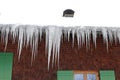 Many large dangerous icicles on a house roof in winter