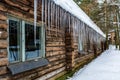 Many large sharp icicles hanging from the roof of the log-house in the snowy forest Royalty Free Stock Photo