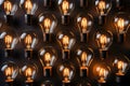 Many light bulbs are lined up flat on black background. Light bulbs repeated pattern dark backdrop