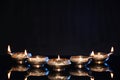 Many lit diyas on black background, space for text. Diwali lamps