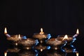 Many lit diyas on black background, space for text. Diwali lamps