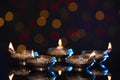 Many lit diyas on dark background with blurred lights, space for text. Diwali lamps