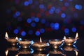 Many lit diyas on dark background with blurred lights, space for text. Diwali lamps