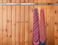 Many mens ties hanging on the rack. Wooden background