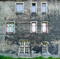 Many messy windows on very old medieval house facade. Royalty Free Stock Photo