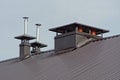 Many metal chimney pipes on a brown roof