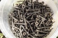 Many metal screws on wood lie in plastic containers, construction concept, tool preparation, top view