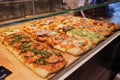 Many mini pizzas on counter. Different types of pizzas in large quantities