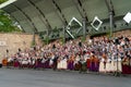 Many mixed folk choir singers in national costumes perform