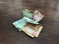 Many mixed mexican peso bills spread over a wooden desk