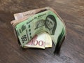 Many mixed mexican peso bills spread over a wooden desk