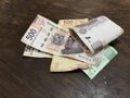 Many mixed mexican peso bills spread over a wooden desk
