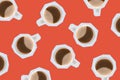 Many mugs with black coffee on a red paper cut background.