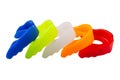 Many multi-colored boxing mouth guards, lie in a row, on a white background