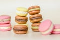 Many multi colored macaroon cakes in stacks on a light background