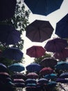 Many multi-colored open umbrellas hang over the street.