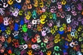 Many multi-colored prints of human hands on a black background.