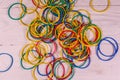 Many multicolored elastic rubbers on wooden table. Top view