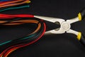 Many multicolored wires and round nose pliers on dark background Royalty Free Stock Photo