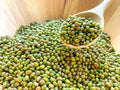 Many mungbean or green beans on a wooden spoon in a wooden bowl