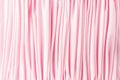 Many narrow vertical folds on a delicate pink fabric. Royalty Free Stock Photo