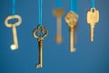 Many old keys of yellow gold color are hanging on thread on a blue background. The concept of the selection of access or password Royalty Free Stock Photo