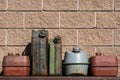 Many old rusty iron fuel cans on a table near the garage, closeup. Various metal painted canisters for gasoline, retro style Royalty Free Stock Photo