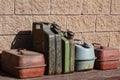 Many old rusty iron fuel cans on a table near the garage, closeup. Various metal painted canisters for gasoline, retro style Royalty Free Stock Photo