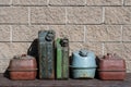 Many old rusty iron fuel cans on a table near the garage, closeup. Various metal painted canisters for gasoline, retro style Royalty Free Stock Photo