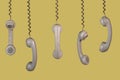 Many old telephone handsets from rotary landlines hanging from cords on yellow background. Plastic grey removed receiver Royalty Free Stock Photo