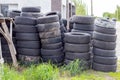 Many old used car tires stacked on top of each other in the grass by the road near the tire shop Royalty Free Stock Photo