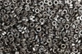 Many old used screw-nuts background, dark shining nuts