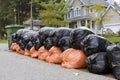 Many orange and green garbage bags at curb