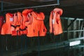 Many orange life jackets hang on hangers on a pier Royalty Free Stock Photo