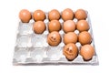 Many orange spotted brown chicken eggs in carton open box container on white backdrop. One egg with black drawn smile Royalty Free Stock Photo