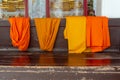 Many of orange and yellow robes of the Buddhist monks are hanging on a table Royalty Free Stock Photo