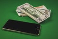 many packs of cash and phone lying on a green background