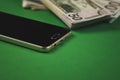 many packs of cash and phone lying on a green background