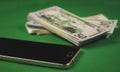 many packs of cash and phone lying on a green background